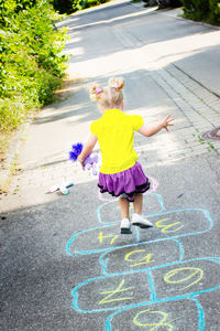 Girl on street playing hopscotch