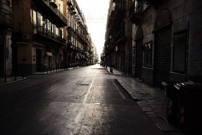 Empty road amidst buildings in city