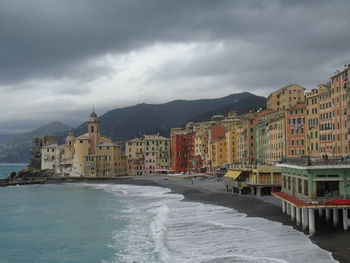 Buildings by sea against sky in city