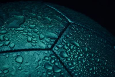 Close-up of water drops on soccer ball against black background
