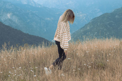 Side view of woman standing on grassy mountain