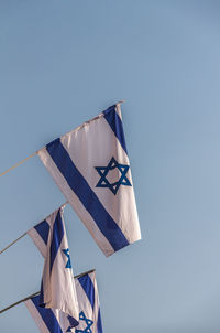 Low angle view of flags hanging against clear blue sky