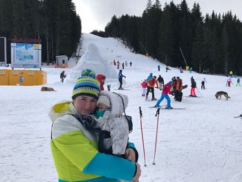 Portrait of mother and son standing on ski slope during winter