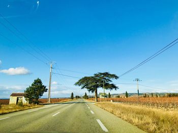 Road by field against blue sky