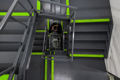 High angle view of man photographing on spiral staircases in industry