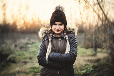 Portrait of young woman in knit hat standing on field