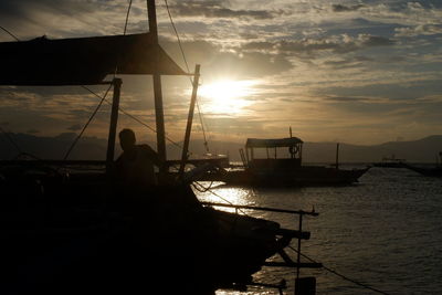 Silhouette sailboats moored on sea against sky during sunset