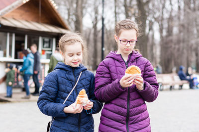 Two girls sisters bought pies in a food truck in a city park and are going to eat