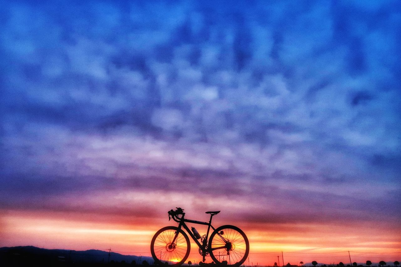 SILHOUETTE BICYCLES AGAINST SKY AT SUNSET
