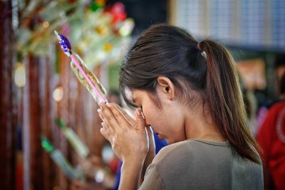 Close-up of young woman praying at temple