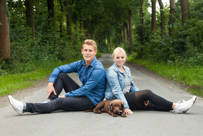 Portrait of couple with dog sitting on road