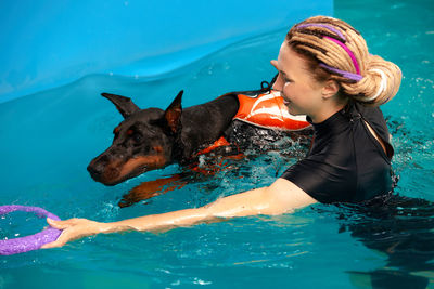 Young woman with dog in swimming pool