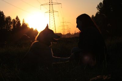 Silhouette woman with dog against sky during sunset