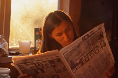 Woman reading newspaper at home