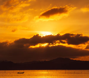 Scenic view of lake against cloudy sky during sunset