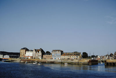 Buildings by river against clear sky