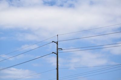 Low angle view of power lines against cloudy sky