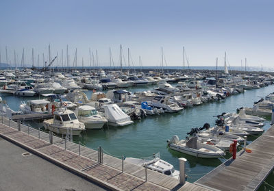 Sailboats moored at harbor against clear sky