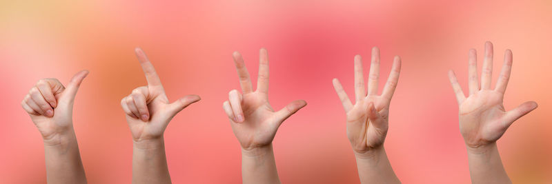 Cropped hands gesturing against colored background