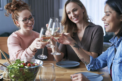 Friends toasting drinks on table