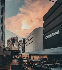 Cars on street against buildings in city during sunset