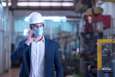 Mechanical worker with mask talking on the phone in a factory person