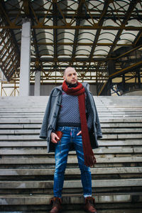 Portrait of man wearing warm clothing standing on steps outdoors