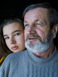 Close-up portrait of girl with grandfather against black background 