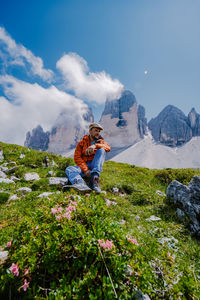 Woman sitting on mountain against sky