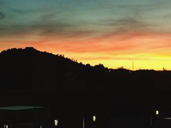 Silhouette trees against orange sky