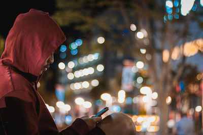 Full length portrait of man photographing illuminated city at night