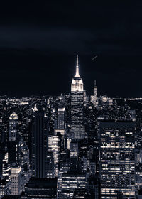 Illuminated buildings in city against sky at night