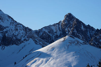 Scenic view of snowcapped mountains against clear blue sky