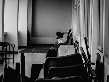 Rear view of woman sitting on chair at home