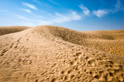 Sand dunes in desert against blue sky