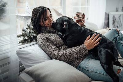 Woman with dog sitting on sofa at home