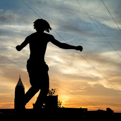 Low angle view of silhouette man standing against sky during sunset