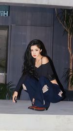 Portrait of young woman standing against wall