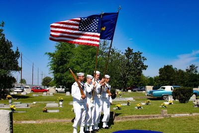 People by flag against blue sky