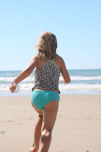 Rear view of woman on beach against sky