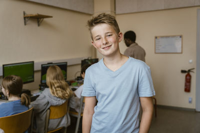 Portrait of smiling male student in computer classroom at school