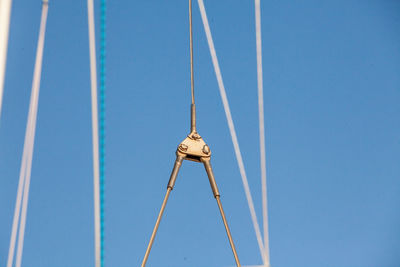 Low angle view of crane against clear blue sky