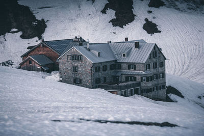 Snow covered houses by building in city