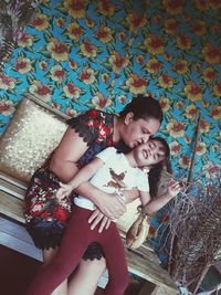 Mother and girl sitting against wall