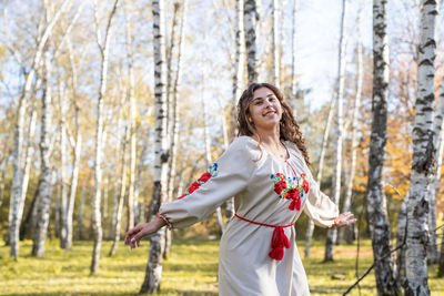 Beautiful woman in national ukrainian national traditional costume clothes dancing in forest