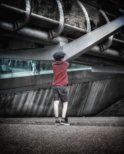 Rear view of a boy standing against built structure