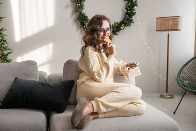 Side view of woman sitting on bed at home