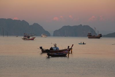 Boats in sea at sunset