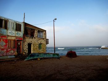 Old building by sea against clear sky