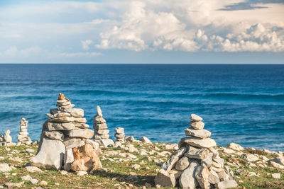 Stone statues by sea against sky